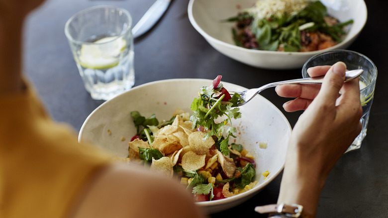 woman eating salad at restaurant 