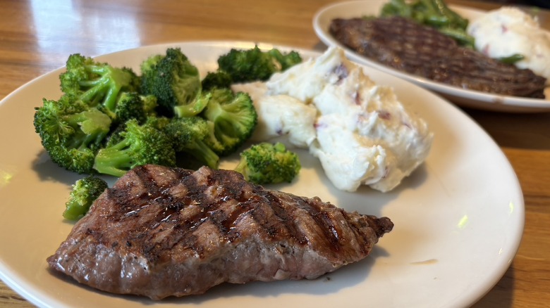 Steaks on plates with potatoes and vegetables