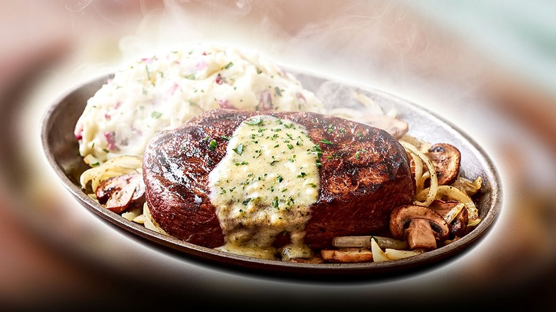 Steaks on plates with potatoes and vegetables