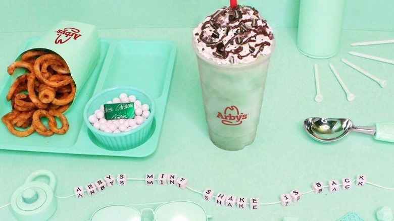 A green background with andes mints, curly fries, and Arby's mint chocolate shake