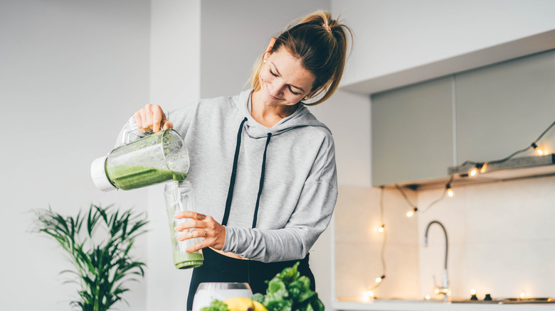 Woman pouring green smoothie into glass