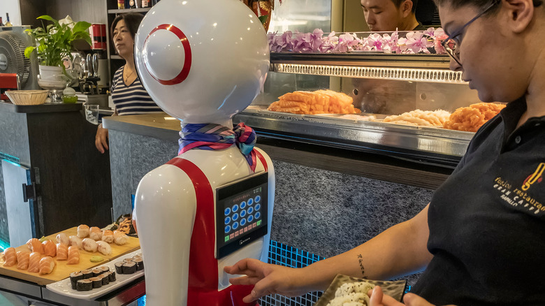 restaurant staff programs robot with tray of food