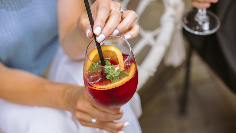 Woman holds cocktail with a straw