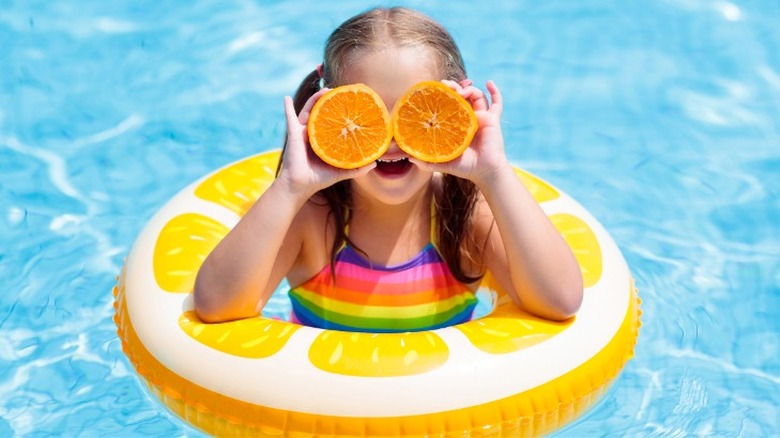 Child in pool with orange slices