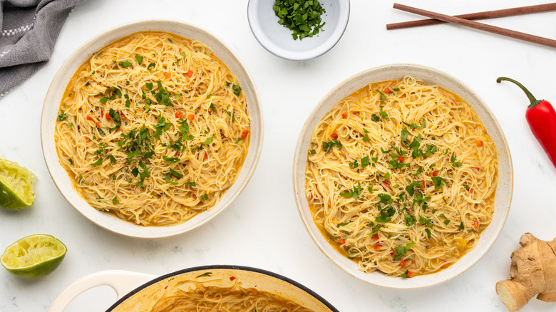 Two bowls of coconut curry noodles with cilantro garnish