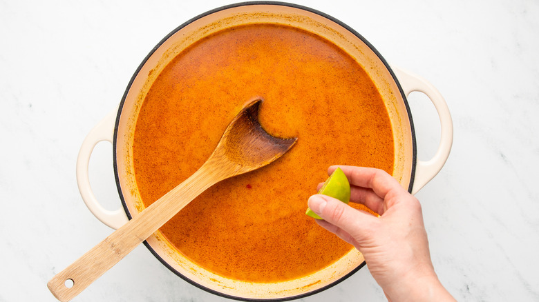 Squeezing lime into pot of coconut curry broth