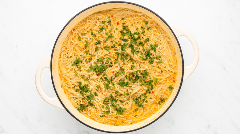 Coconut curry noodles with cilantro garnish in casserole pot