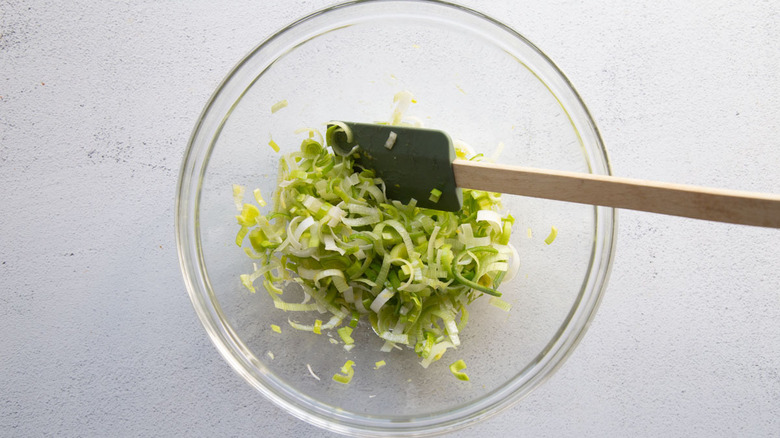 stirring sliced leeks in bowl