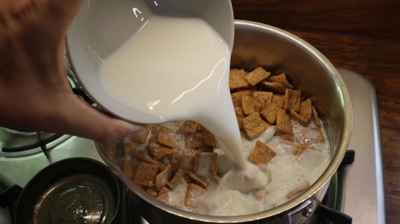 pouring milk into saucepan of cereal