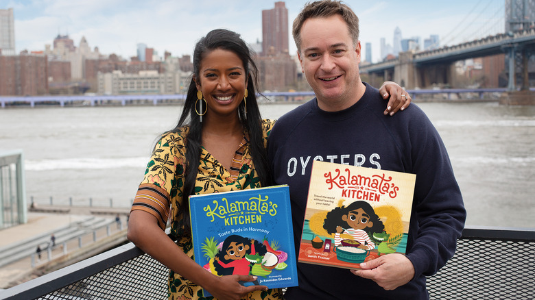 Sarah Tomas and Derek Wallace holding books in front of water