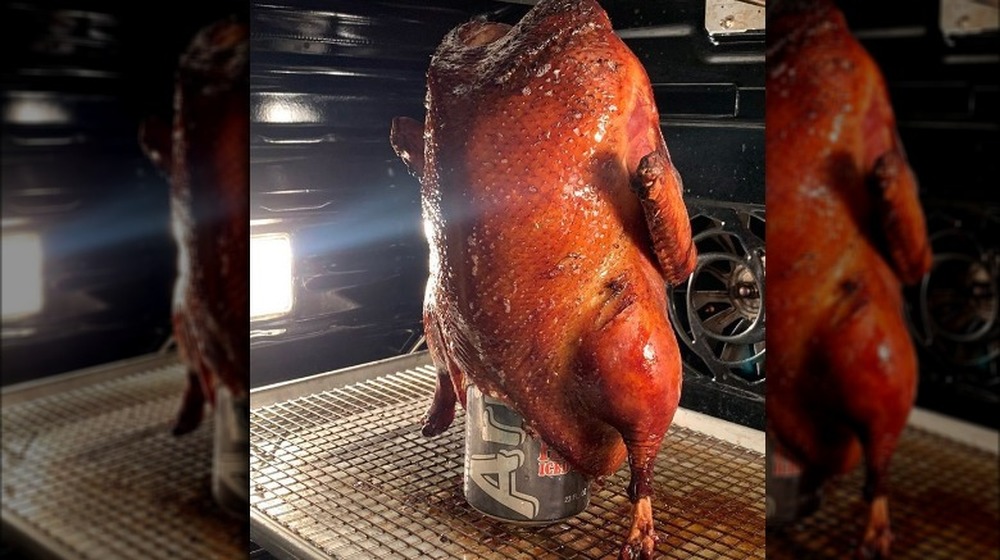 Cooked duck in oven roasting vertically, propped on aluminum can. 