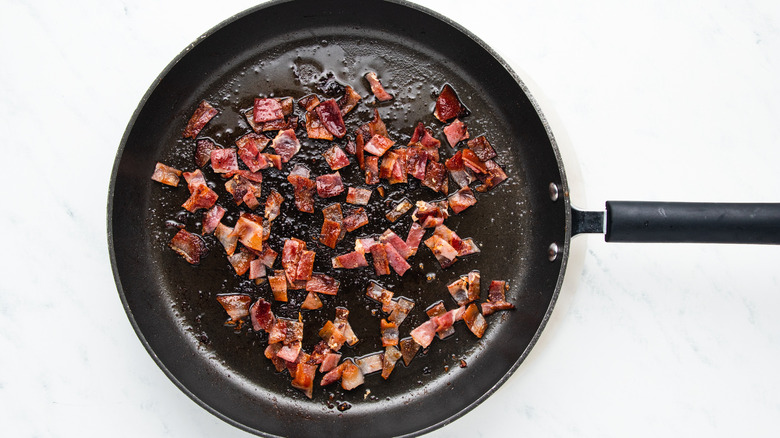 Chopped bacon frying in pan