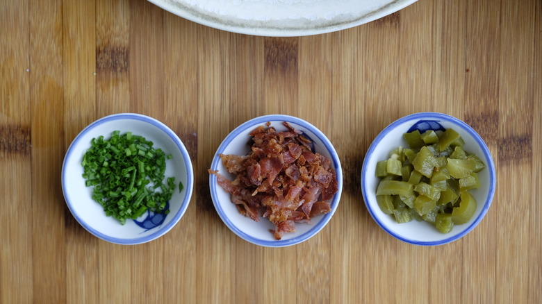 Chives, bacon bits, and jalapenos sit in bowls