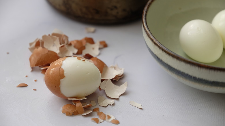 A cracked hardboiled egg sits on a surface