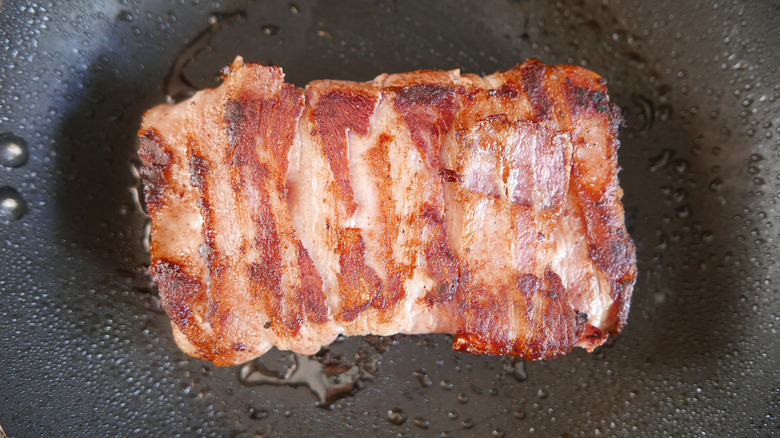 Bacon wrapped sandwich cooking in a pan