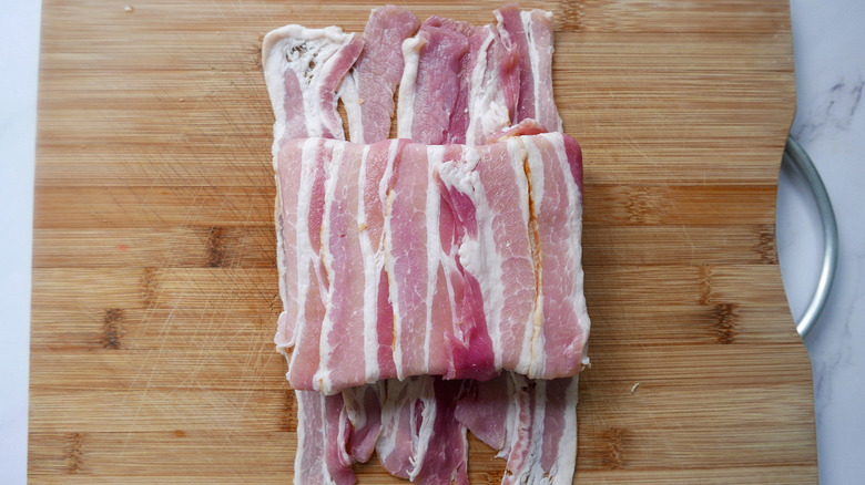 A bacon wrapped sandwich on a cutting board