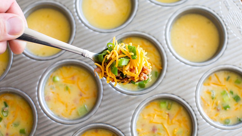 eggs in muffin tin cheese and peppers on spoon