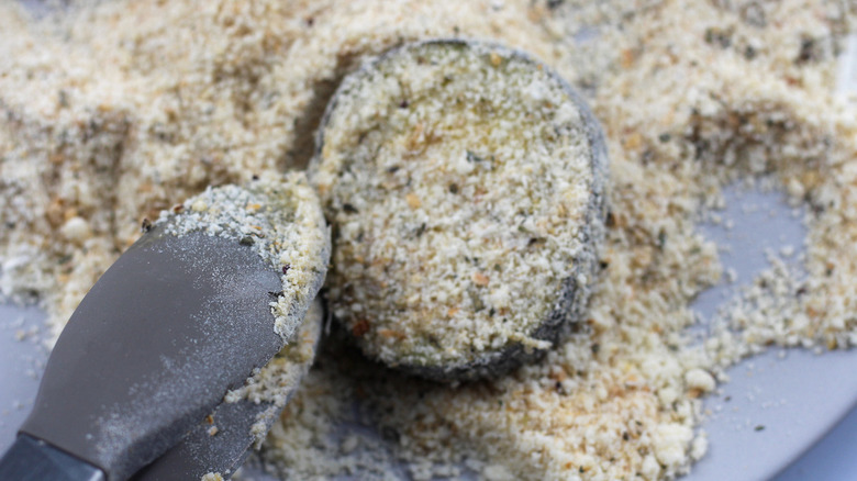 An eggplant disc dipped in a breadcrumb mixture.