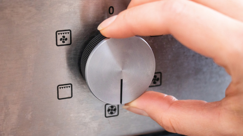 Hand turning dial on oven