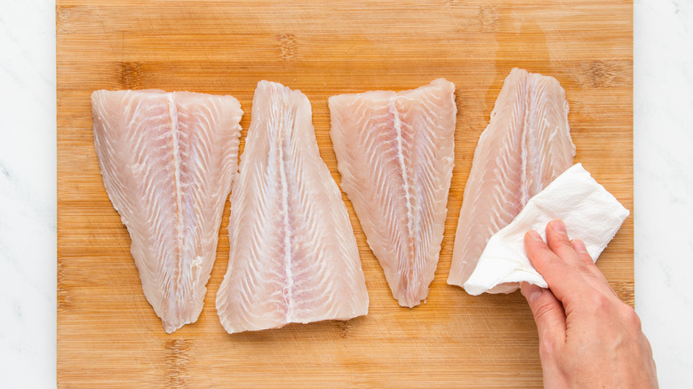 Tilapia fillets being patted dry