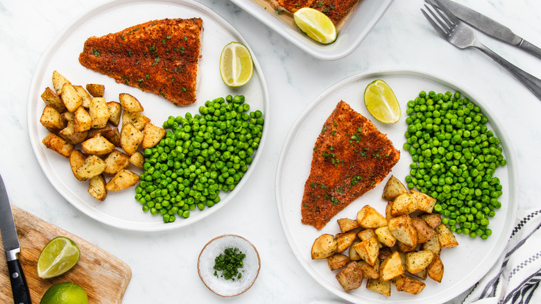 Baked tilapia served on plates with potatoes and peas