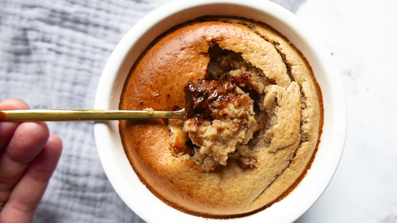 Spoon breaking into ramekin of baked oatmeal