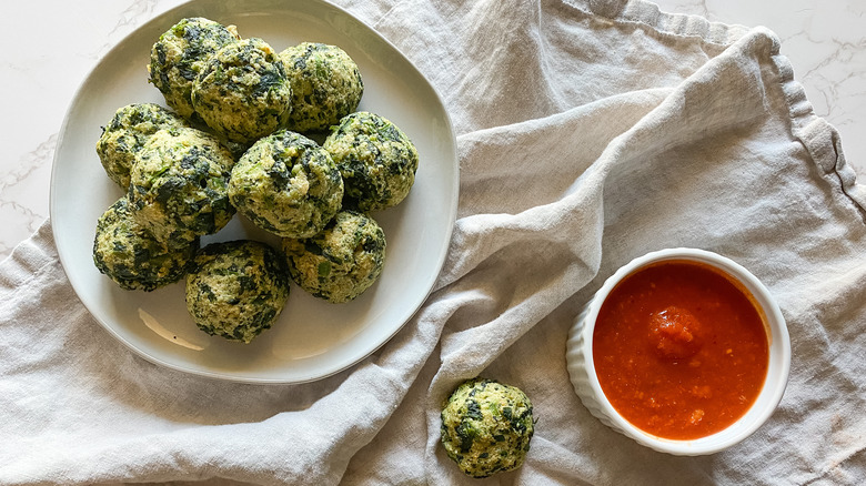 Parmesan spinach balls on a plate next to marinara