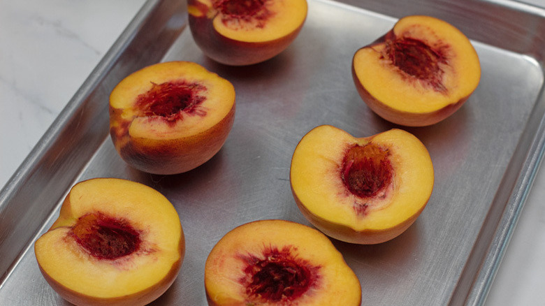 halved peaches on baking sheet