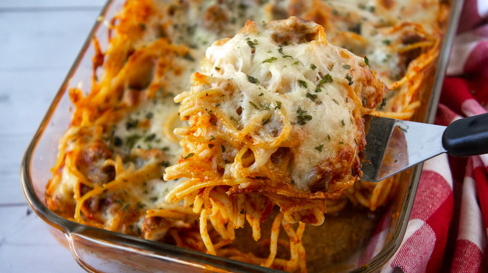 A baked spaghetti casserole with a scoop being lifted out