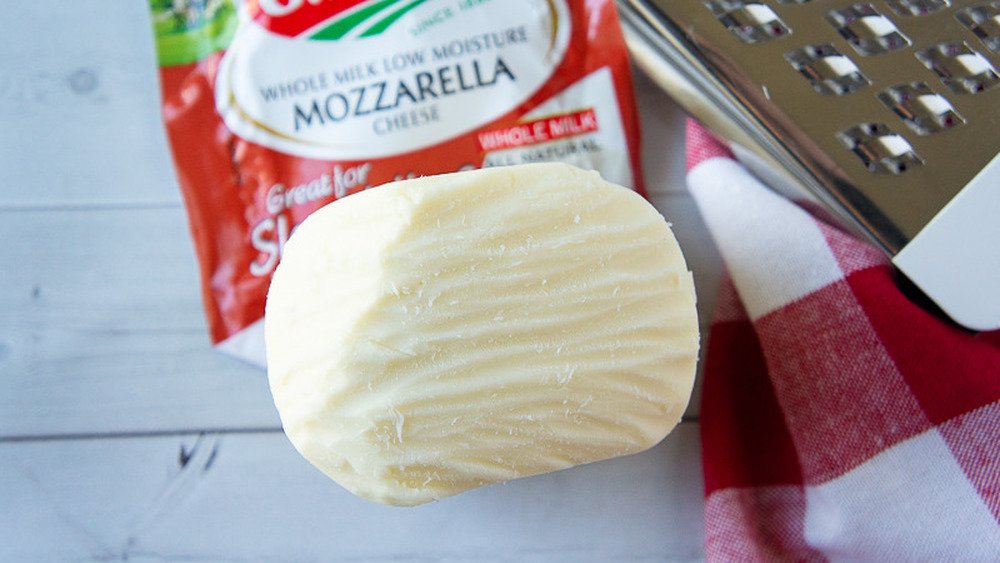 a block of low moisture mozzarella cheese with a grater