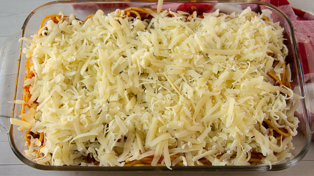 a casserole dish of spaghetti noodles with sauce topped with cheese