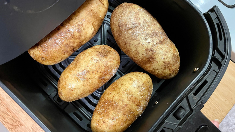 oiled and seasoned potatoes in an air fryer basket