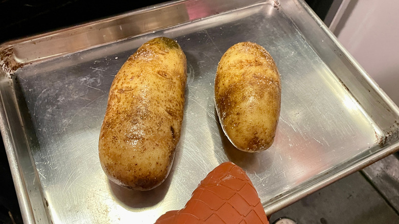 potatoes on a sheet tray going into an oven