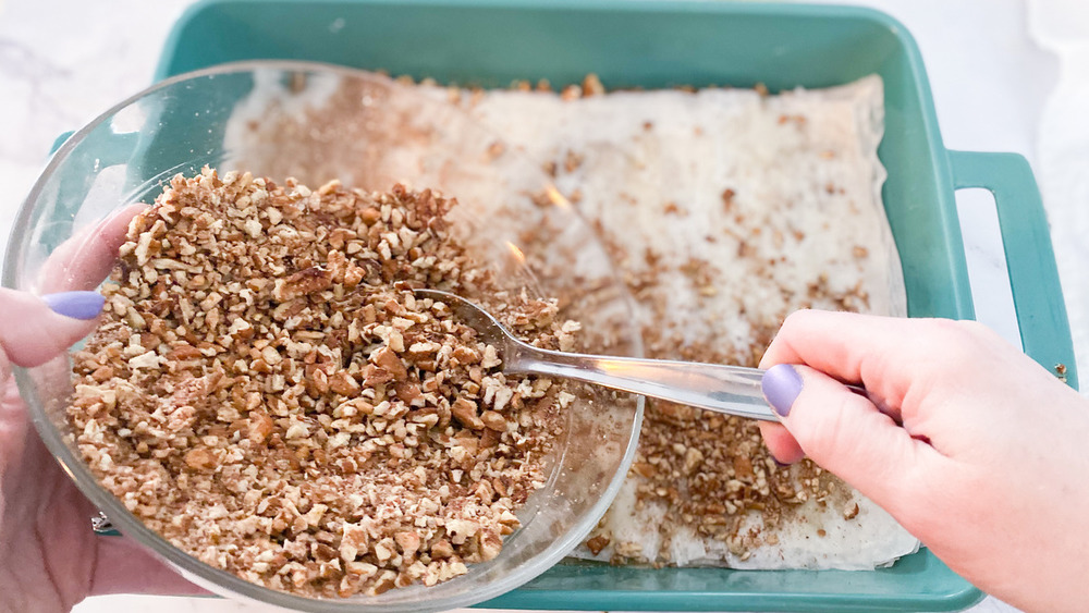 Sprinkling chopped pecans onto phyllo layers