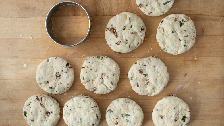 cut out biscuit dough rounds on wood board