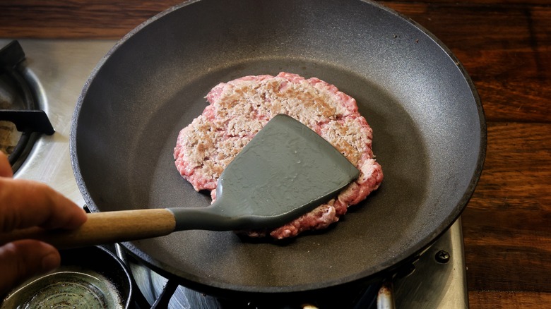 spatula smashing burger in skillet