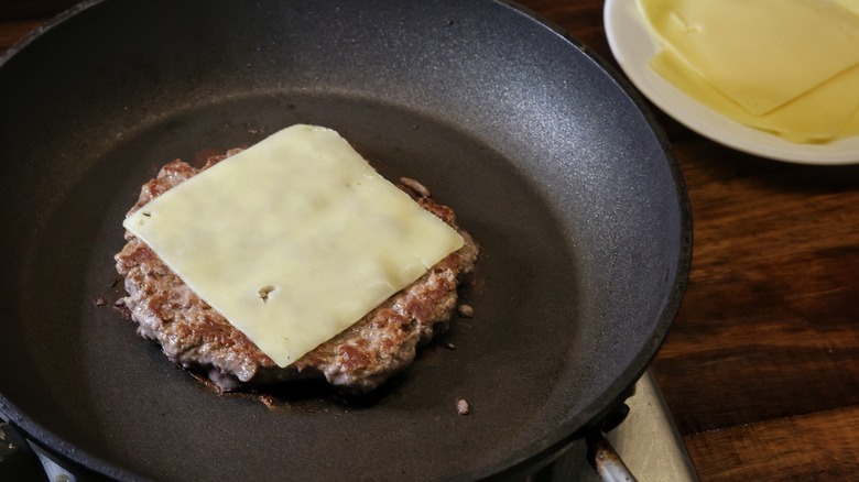 burger patty with cheese in skillet