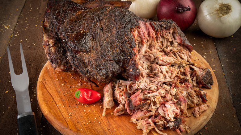 shredded pork with large knife on cutting board