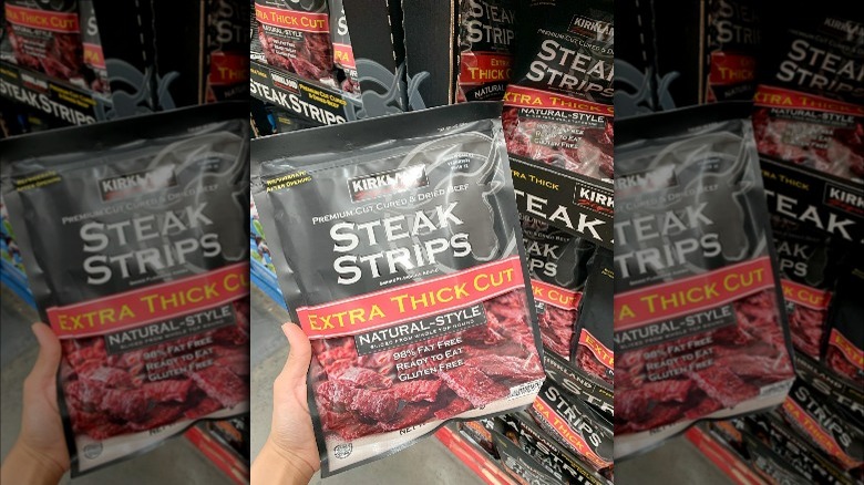 Someone holding Kirkland Signature Steak Strips in store