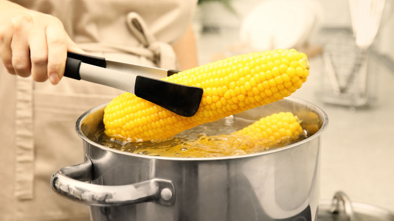 person holding boiling corn cobs