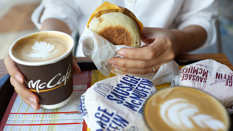 person holding McMuffin and coffee