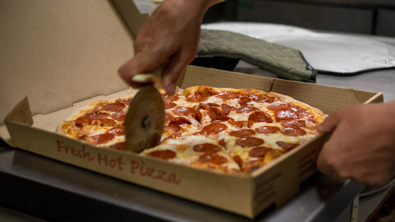 hand cutting a pizza