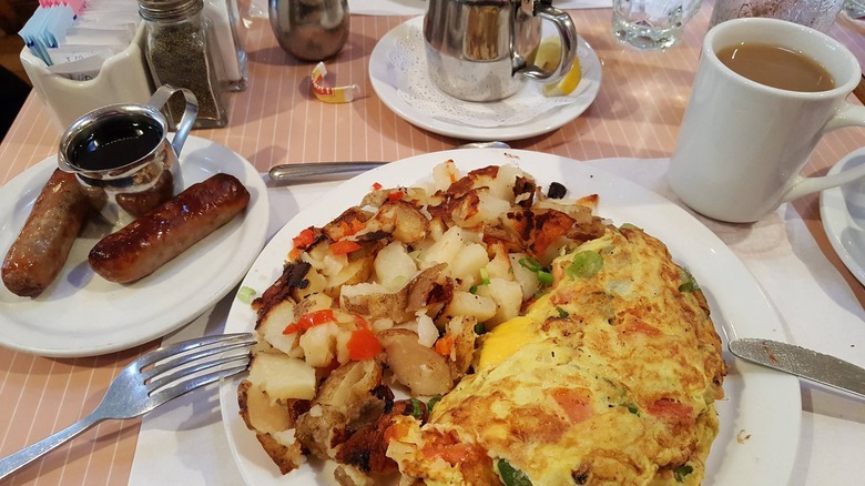 Omelet and sausage with coffee on pink table