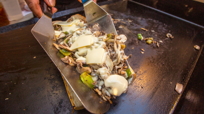 Cheesesteak cooking on flat-top grill