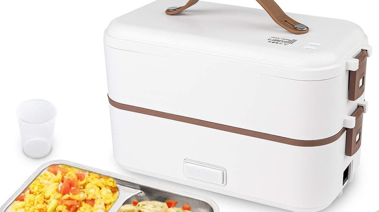 A white lunchbox rice cooker on a white background with food in front