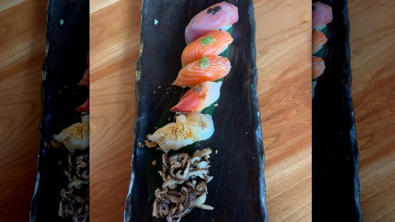 Line of sushi on black plate