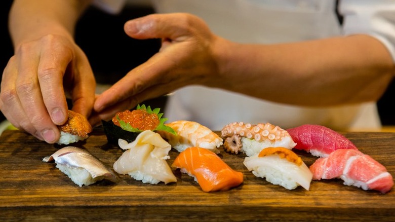 Hand serving sushi pieces