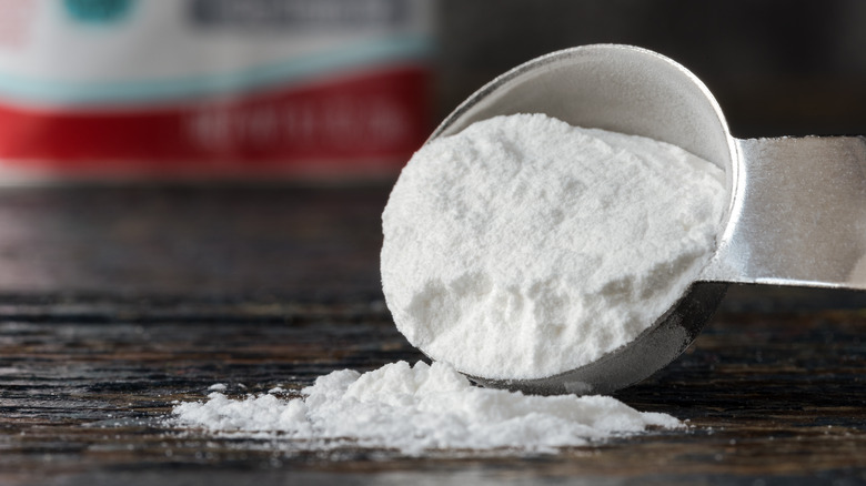 measuring spoon of baking powder spilling onto table