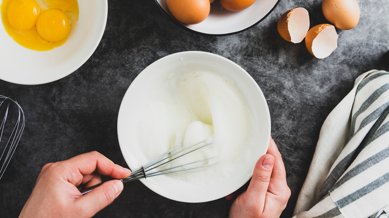 hands whipping egg whites with whisk