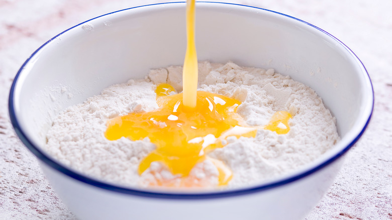 melted butter pouring into white enamel bowl of flour